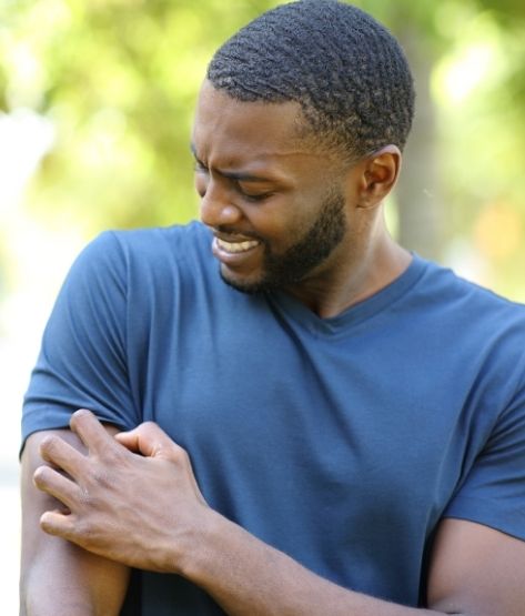 Black Man Scratching Itchy Arm in a Park