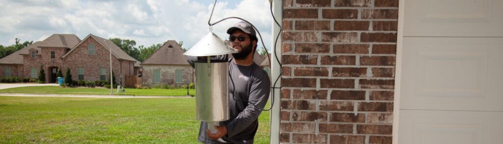 Mosquito control professional installing a mosquito surveillance trap in a residential community