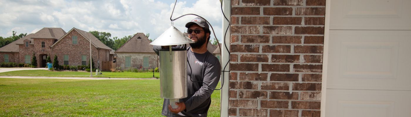Mosquito control professional installing a mosquito surveillance trap in a residential community
