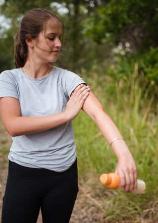 girl putting mosquito repellent on arm